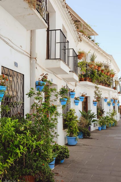 White house wall with blue flowerpots along a village lane