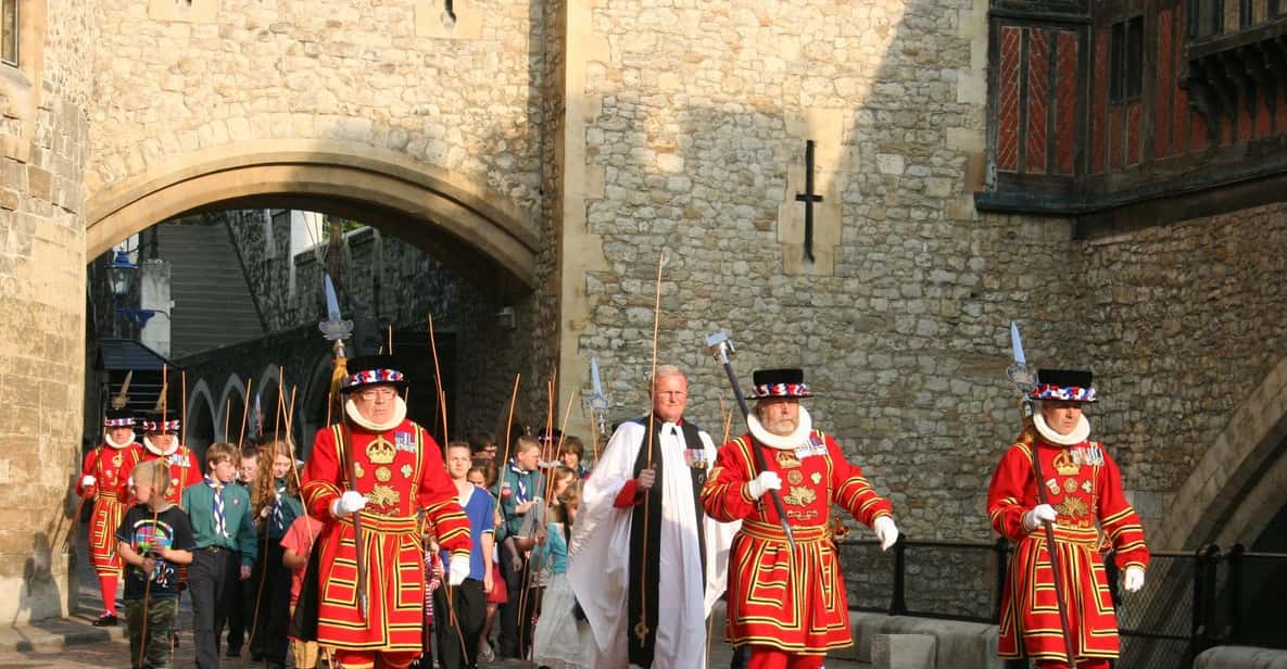 Yeoman Warders in ceremonial red and gold state dress walking through a stone arch at the Tower of London
