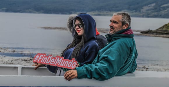 Weißer Katamaran auf dunkelblauem Wasser unter verschneiten Bergen im Beagle-Kanal