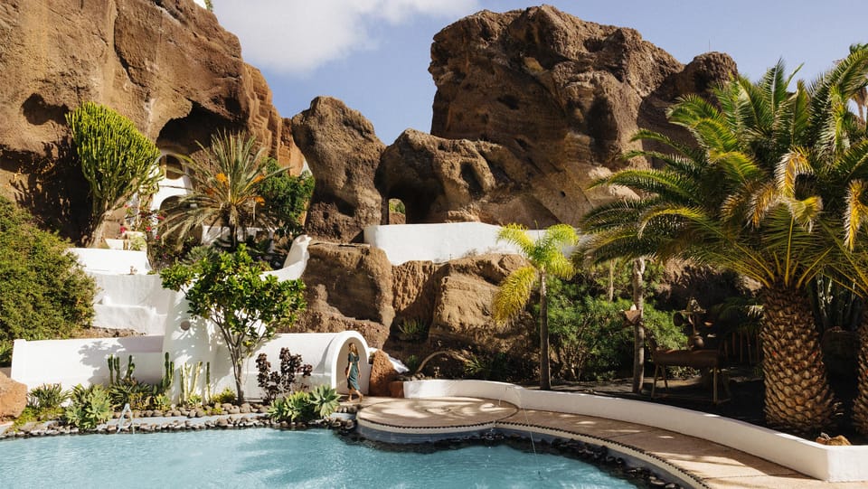 White terraces and a pool set against the brown quarry rock at LagOmar in Nazaret