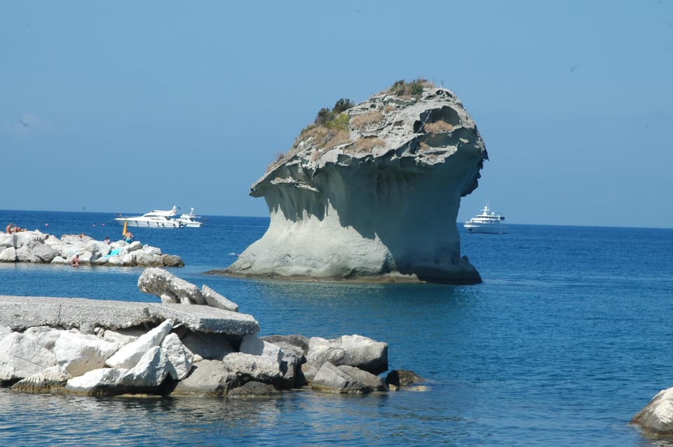 A small bus following a coastal road above the sea on Ischia