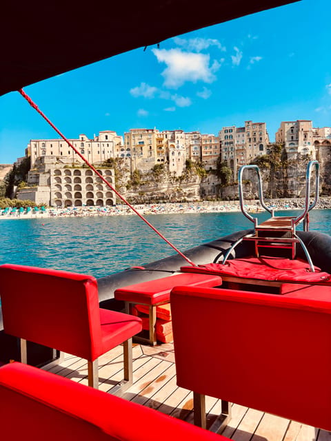 View from a dinghy with red seats towards the cliffs and houses of Tropea