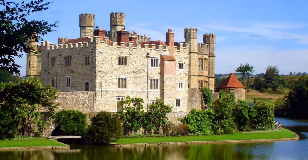 Leeds Castle on its lake, with visitors walking the lawn beside the water