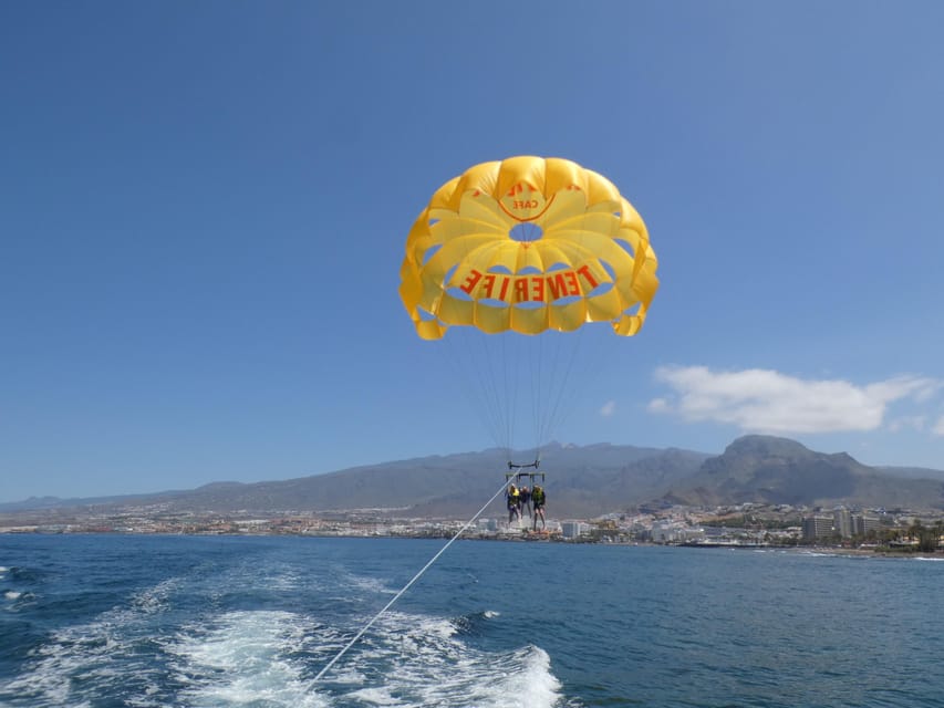 Parasail canopy flying behind a boat over a blue bay
