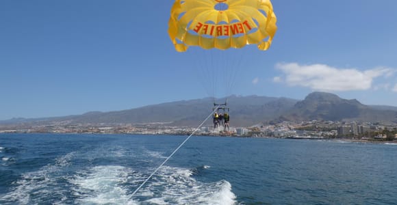 Parasail canopy flying behind a boat over a blue bay