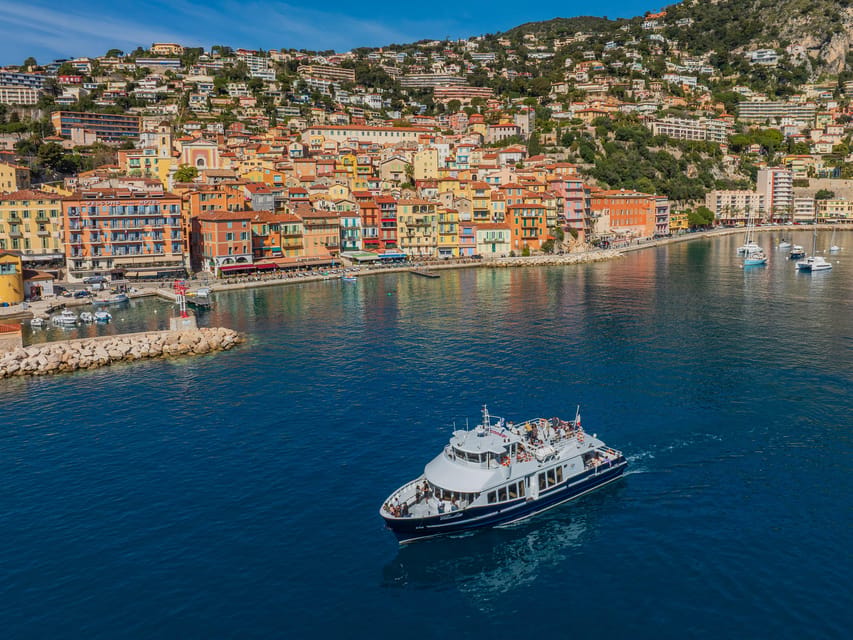 A sightseeing boat crossing the deep blue water in front of the colourful houses of Villefranche
