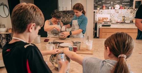 Children preparing pale gelato mixture with utensils at a bright cooking counter in Bologna