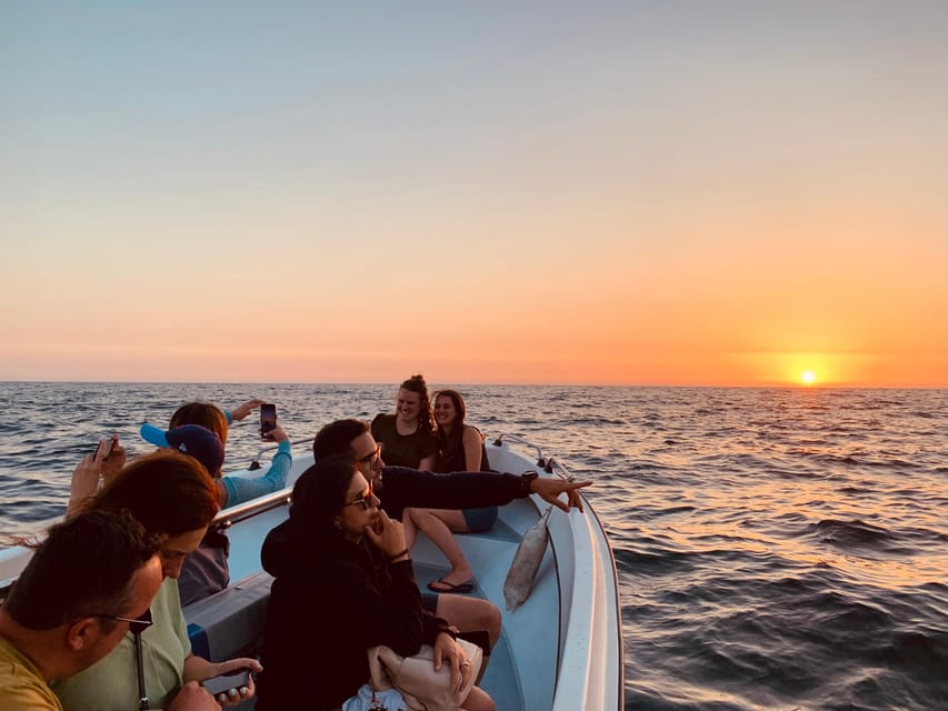 People on a small boat watching the sun set over the open sea