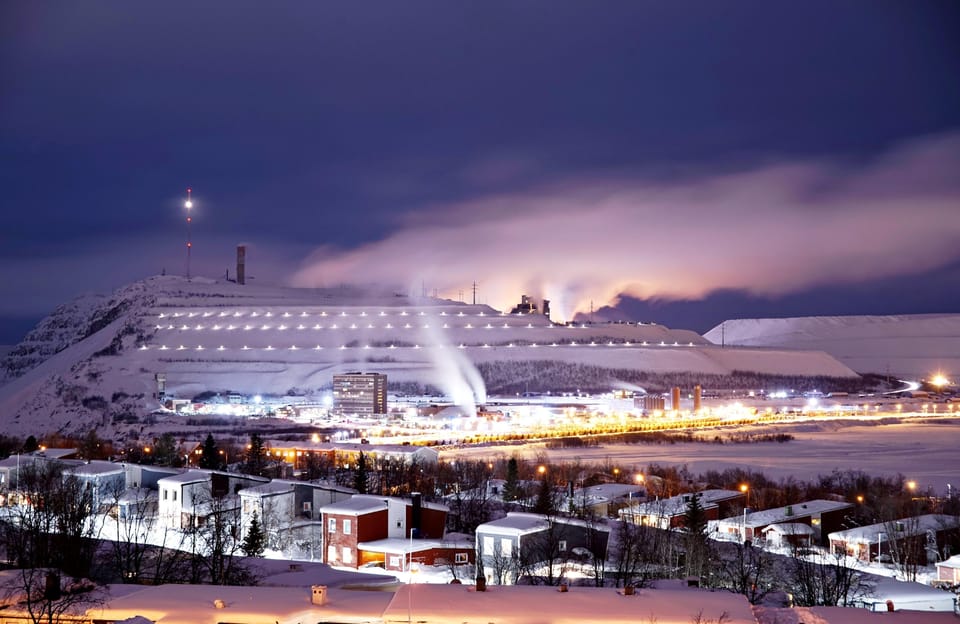 Kiruna at night with the illuminated mine mountain Kiirunavaara behind snowy houses