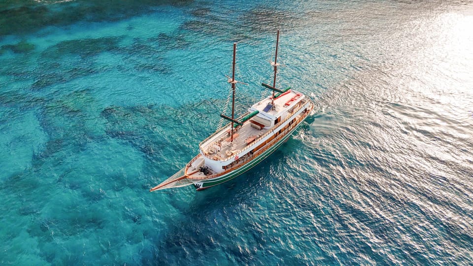 Traditional wooden excursion boat on calm water beneath an orange evening sky