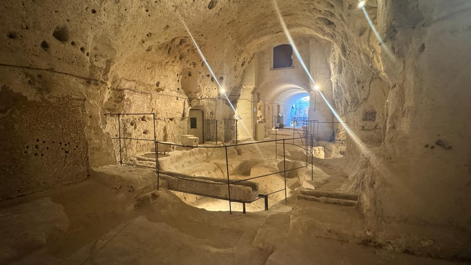 Warmly lit rock-cut chamber with rough limestone walls and a narrow passage