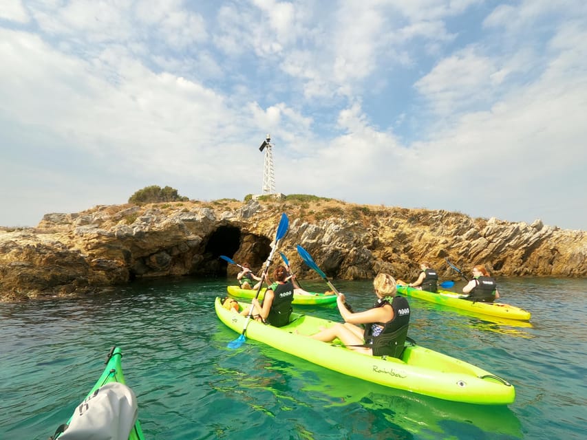 Two sea kayaks pulled up on a small cove of pale pebbles beneath rocky cliffs
