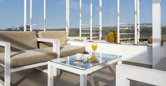 Armchairs and small tables arranged beside large windows in a quiet airport lounge
