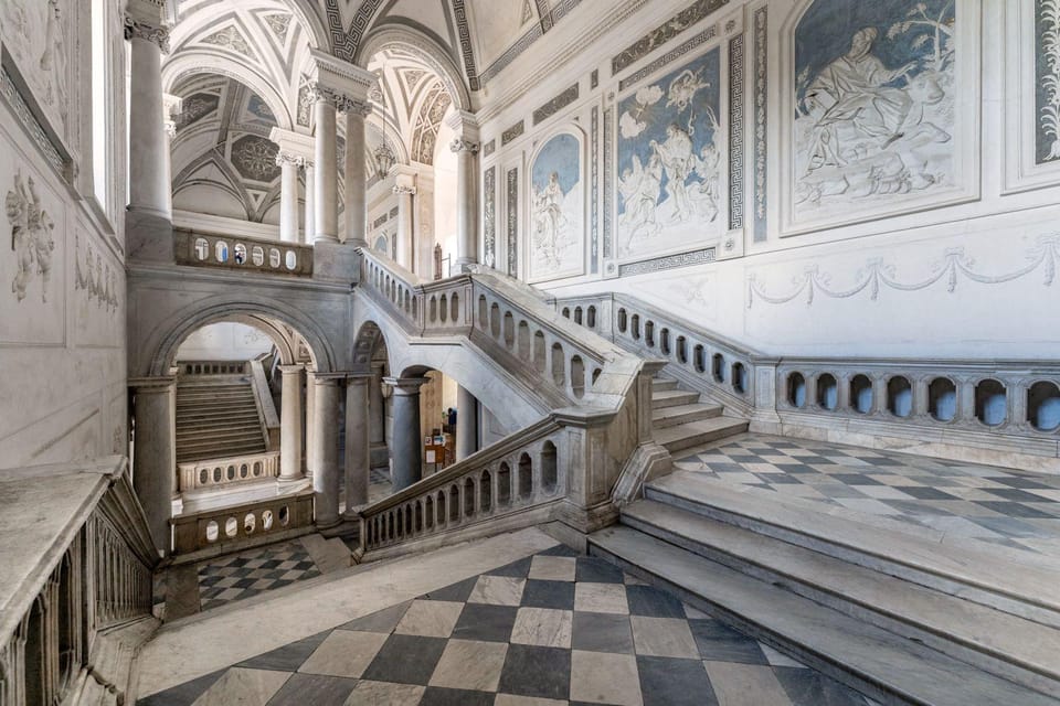 Marble staircases with a chequerboard floor and wall paintings in a baroque stairwell