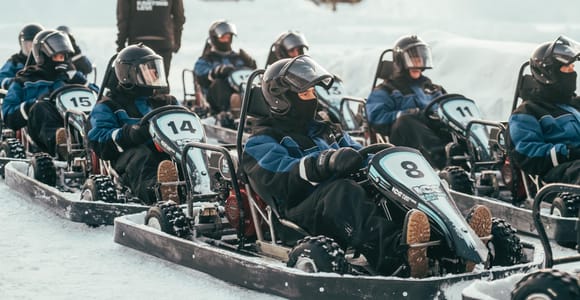 Studded go-karts taking a bend on a floodlit ice track in Levi