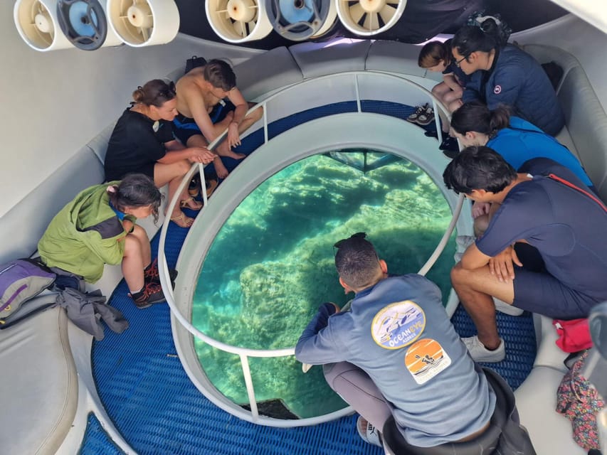 Passengers looking through viewing panels into clear Atlantic water from a small boat near São Miguel