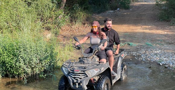 A rider on a quad following a dusty forest trail through pine-covered hills near Fethiye