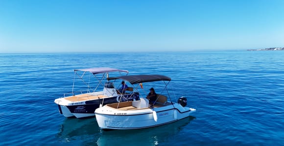 Two small open motorboats with canopies side by side on calm deep-blue sea