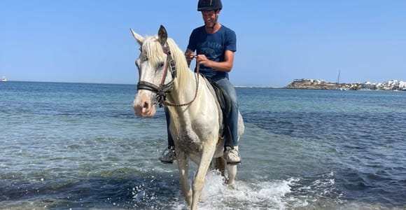 Two riders following a sandy track beside reeds near Saint George Beach on Naxos