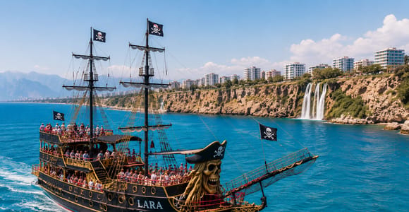 The pirate-style tour boat Lara Pirate off Antalya’s cliffs, with a waterfall dropping into the sea behind