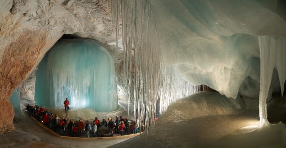 Frozen ice formations lit inside a dark mountain cave with a wooden staircase leading upward