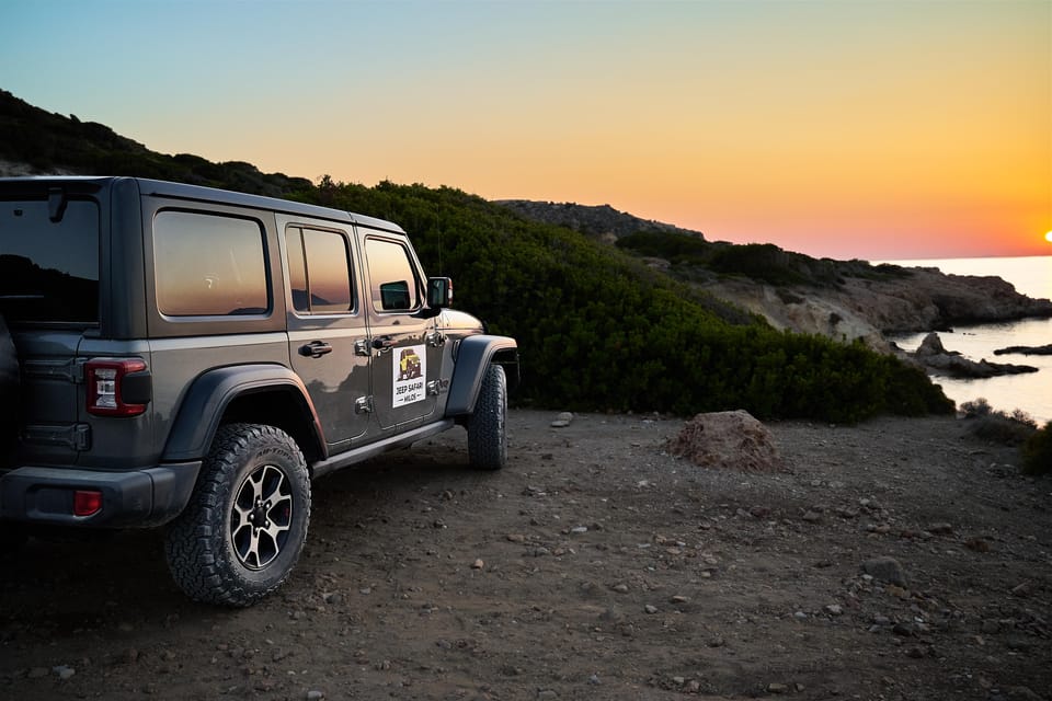 Open off-road vehicle parked on a dusty track above a pale rocky coastline with the sea beyond