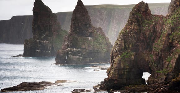 Low stone walls of a prehistoric settlement beside a windswept northern bay