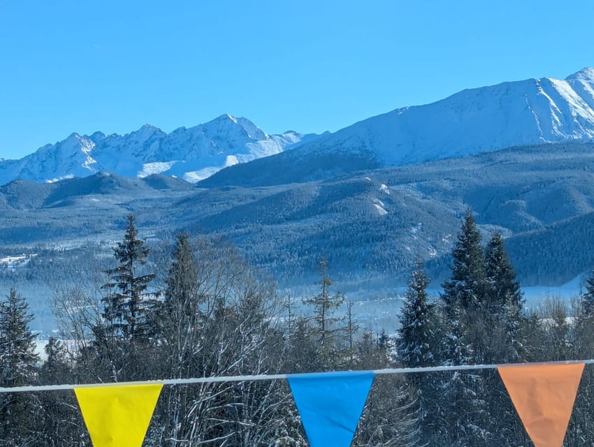 Snowy spruce forest with coloured pennants in front of snow-covered Tatra peaks