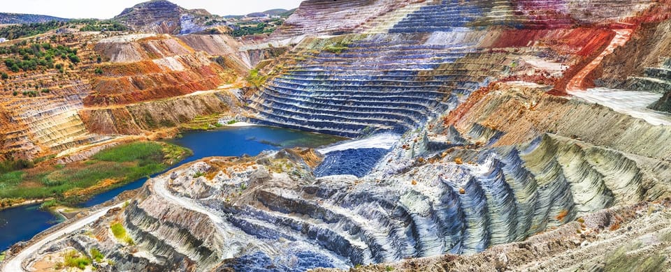 Colourful terraces of an open-pit mine on Milos with a small lake in the hollow