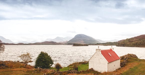 A single-track Highland road winding between rocky hills towards the coast