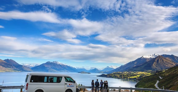 A minibus beside a broad valley of braided rivers and steep green mountains near Glenorchy