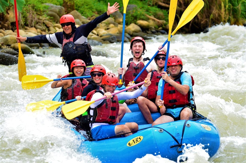 A rafting team paddling through white water between forested riverbanks