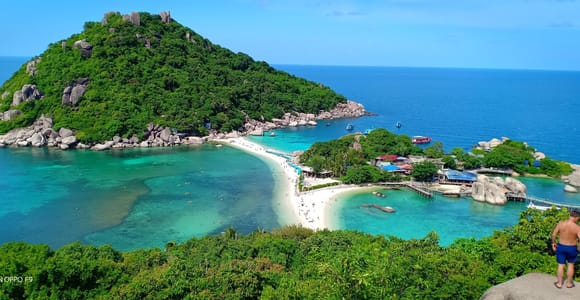 A speedboat moored beside clear turquoise water and a forested island