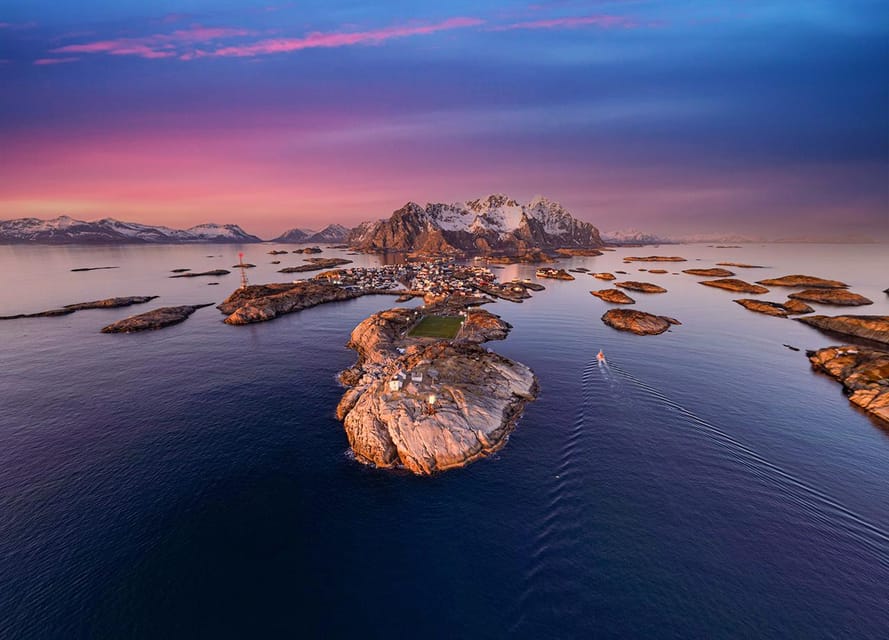 Red fishing cabins clustered around a sheltered Lofoten harbour beneath steep rock walls