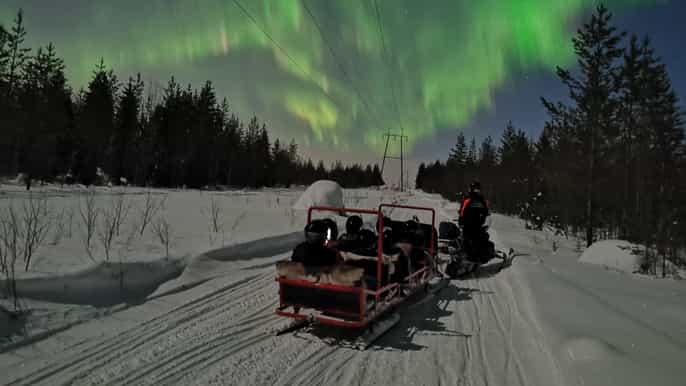 northern lights sledge ride pulled by snowmobile