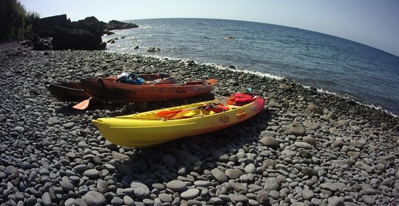 Kayaks floating above clear blue water beside Madeira’s rocky coast