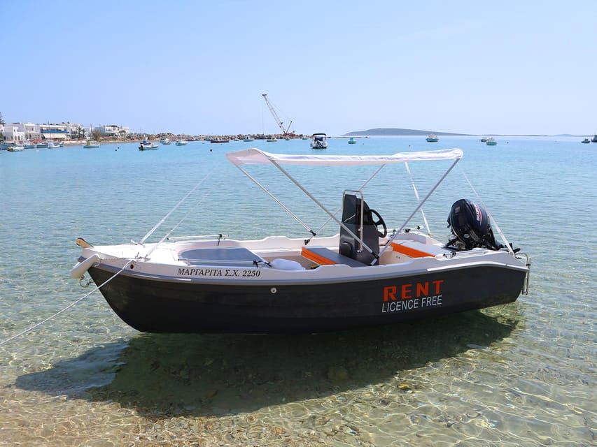 A small open motorboat floating beside a sheltered rocky coast in clear water