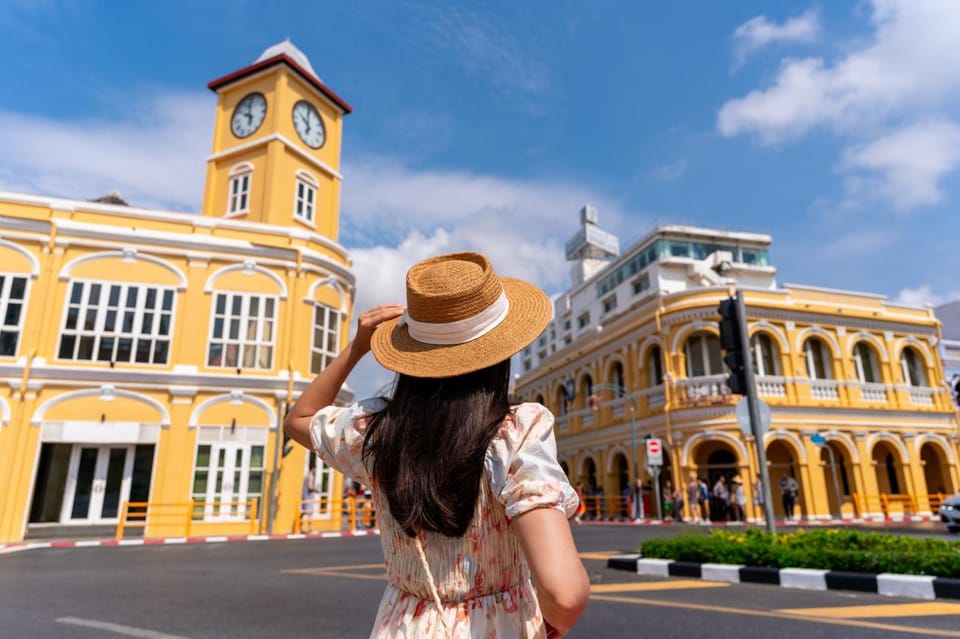 Photographer framing a shot down a narrow lane of colourful shophouses in the late afternoon
