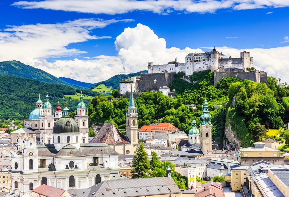 Cyclists and pedestrians crossing a bridge towards Salzburg's old town and fortress