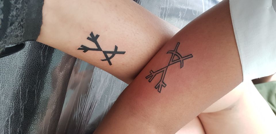 Black arrow with roman numbers sibling tattoos on inner arm