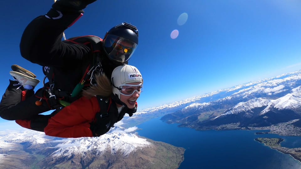 A person in a harness suspended above a deep rocky valley near Queenstown