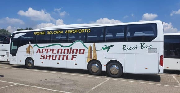 White coach marked “Appennino Shuttle” and “Firenze Bologna Aeroporto” parked in a car park