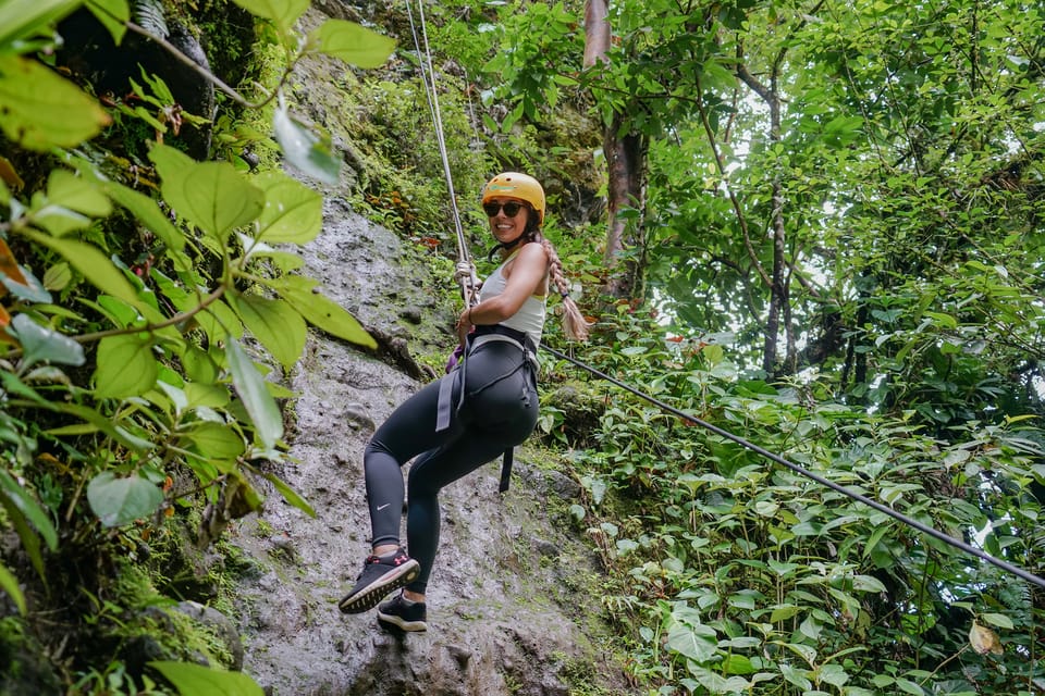 A traveller gliding on a cable above dense green rainforest near Arenal