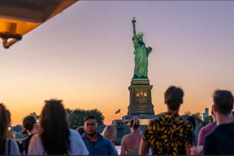 Sunset cruise passing the Statue of Liberty with golden hour views