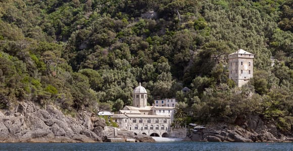 The stone abbey of San Fruttuoso beside a clear cove and wooded slopes