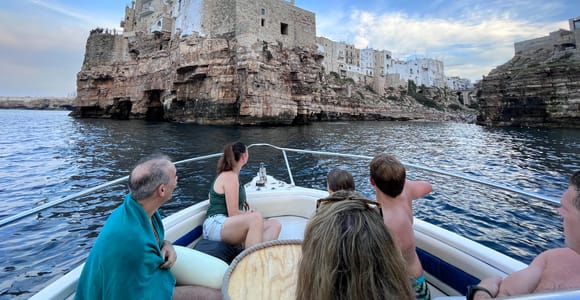 A white motorboat travelling along the rocky Adriatic coast between Monopoli and Polignano