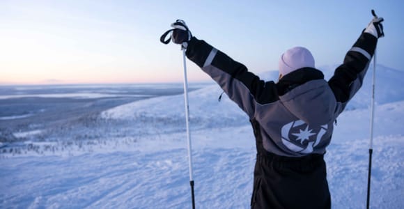 Person raising ski poles on a snowy fell in the dusk light