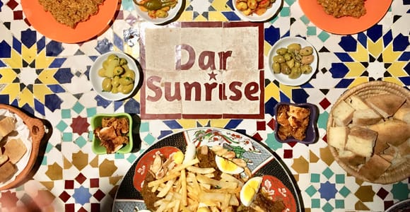 Moroccan dishes, olives and bread on a table with colourful tile mosaic