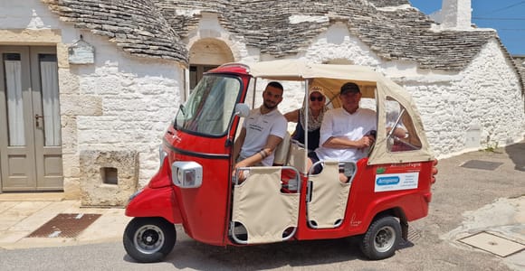 White trulli with conical limestone roofs lining a sloping street in Alberobello