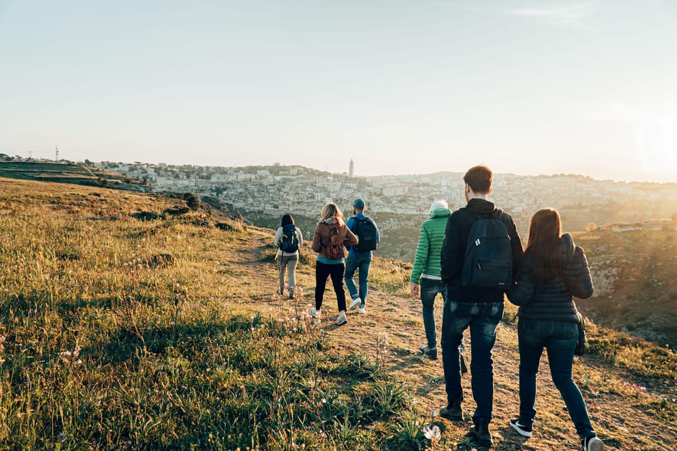 Small group walking towards a viewpoint over Matera in low evening light